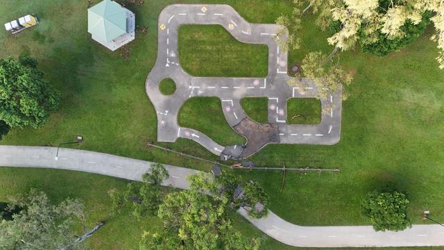 A straight down perspective of a kids cycle path, showing traffic markings, traffic signs etc.  A section of track is washed away