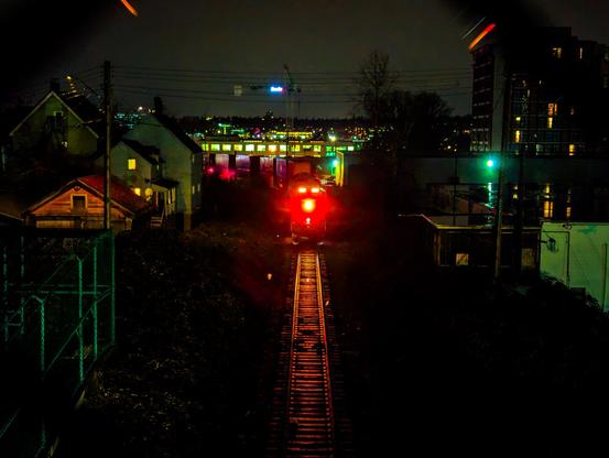 a head of a train with a bright red light, highlighting rail in front of it