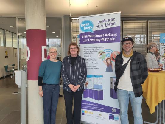 Die Geschäftsführung des Diakonischen Werkes Baden-Baden und Rastatt gemeinsam mit einer Mitarbeiterin von FreiJa Freiburg vor einem Roll-Up zur Ausstellung der Loverboy-Methode im Foyer des Landratsamtes Rastatt.