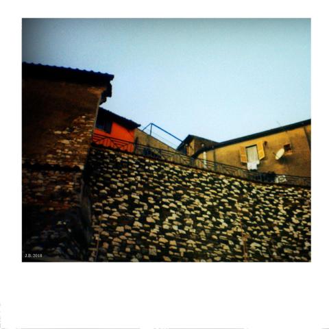 Color photo taken during a walk in the small town of Monterotondo, Lazio, Italy with a point-and-shoot Konica camera. View up a stone wall towards the houses and sky above.