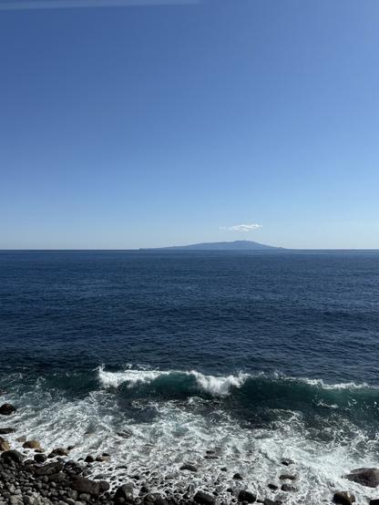 Vue depuis le train sur la mer au pied des rails et une île au loin