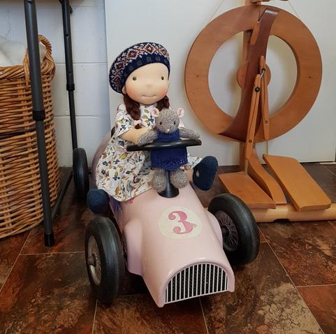 Waldorf-inspired and her toy mouse sitting on a pink car