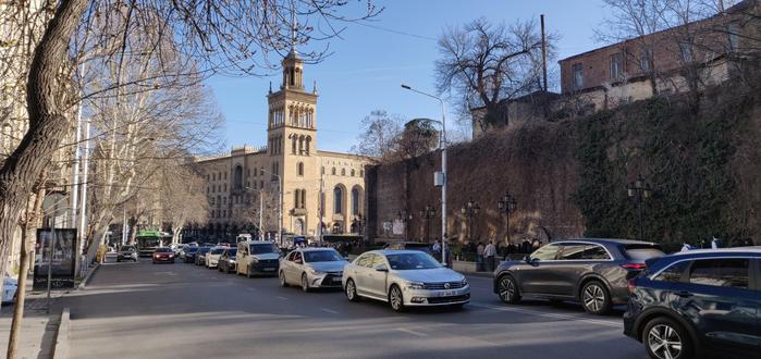 Street scene in Tbilisi, avenue Rustaveli with the historical university stone building in the background.