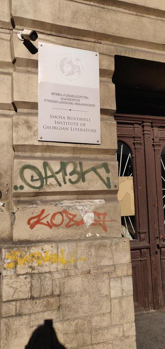 Entrance to the Shota Rustaveli Institute for Georgian Literature. A massive old stone building with the institutes's name and symbol on it.