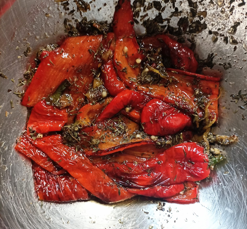 Die gegrillte Paprika zum Marinieren mit den Gewürzen in einer Schüssel