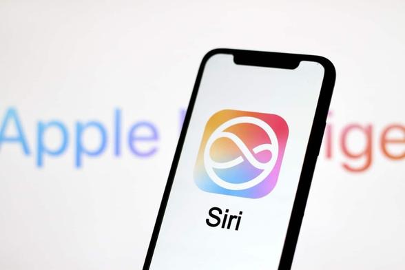 iPhone mit Siri-Schriftzug und -Icon vor weißem Hintergrund, wo unscharf „Apple Intelligence“ geschrieben steht.