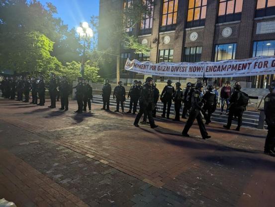 A line of UMPD officers in riot gear prepare to violently sweep the Palestine solidarity encampment at the University of Michigan