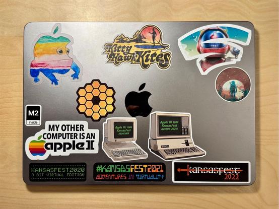 Picture of a closed MacBook Air laptop on a desk covered in retro computing and gaming stickers