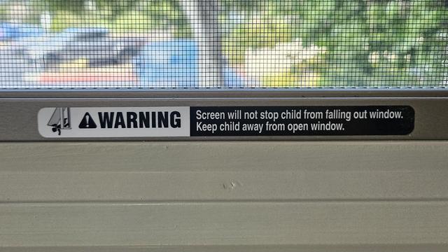 Close-up of window screen in CIO Office at Monterey-Salinas Transit that reads "WARNING Screen will not stop child from falling out window. Keep child away from open window."