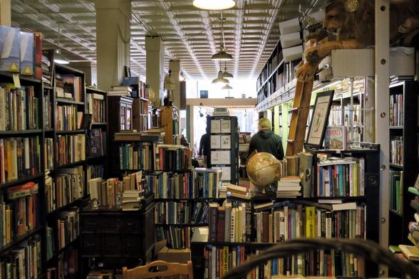 Books on shelves everywhere! Light comes from the far window onto the street.