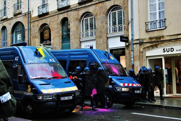 Deux cars de CRS et des CRS repeints en rose par des ballons de baudruche de peinture