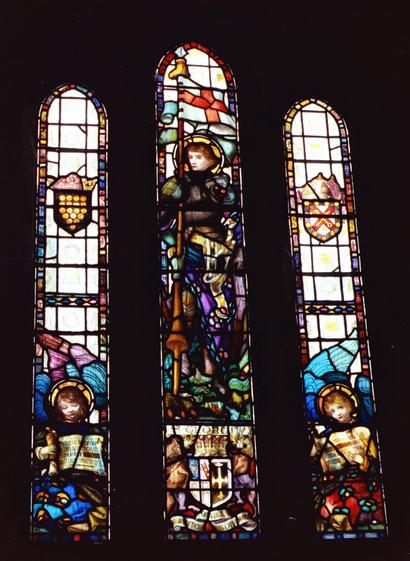 Stained glass window from St. Materiana's Church, Tintagel. It has three panels, with the left panel depicting Cornwall Coat of Arms (15 gold coins) with an angel reading a scroll below. The right hand panel has an unknown ( to me) crest with a crossed key and sword, with an angel below reading a scroll. The centre panel features St. George in armour holding a lance with his Pennon flying (red cross on white background). He is stood over a dragon, and the bottom of the panel contains another crest flanked by a horse and a deer (possibly).