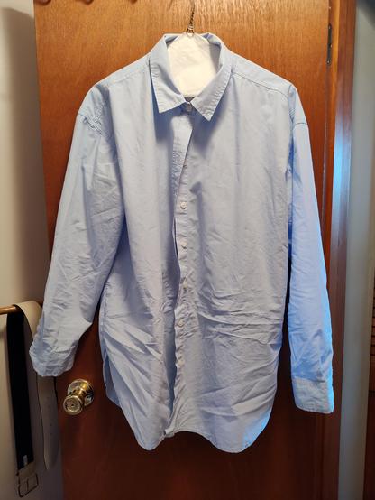 Front of a pale blue cotton button down shirt with major wrinkles just from trying it on.