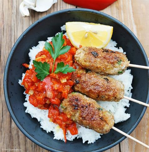 Holzuntergrund. Schwarze Bowl mit Cevapcici, Reis und selbst gemachtem Ajvar