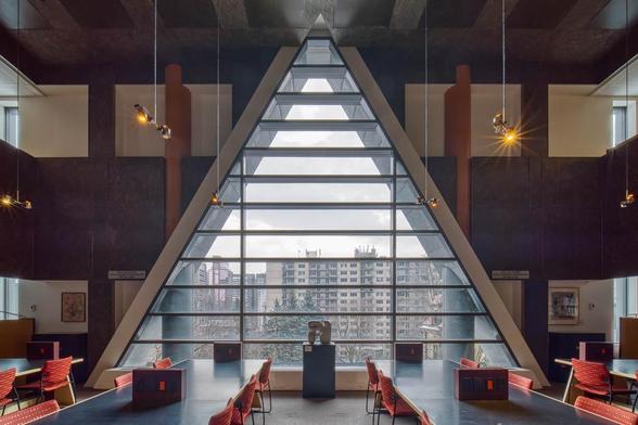 Interior of a library reading room with a large triangular window.