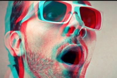 A man wearing 3D glasses with the image having red and blue shadows