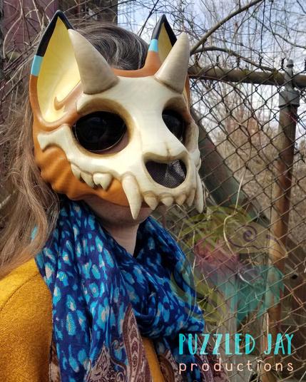 Several photos of Cass wearing an orange wolf mask, featuring an exposed skull element with horns, similar to the Pokemon Cubone