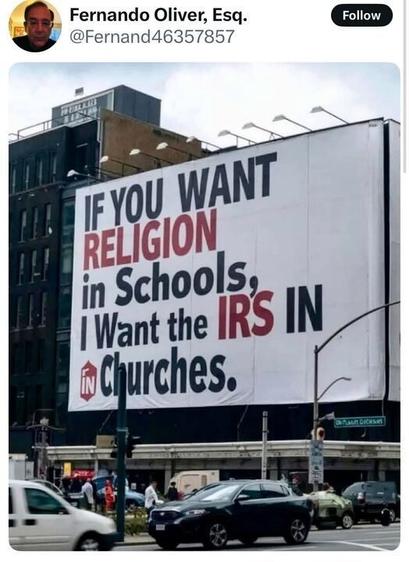 A tweet from Fernando Oliver, Esq. (@Fernand46357857) featuring a large billboard on the side of a building. The billboard reads: "IF YOU WANT RELIGION in Schools, I Want the IRS IN Churches." The words "RELIGION" and "IRS" are highlighted in red, while the rest of the text is black. The image captures a busy urban street with cars and pedestrians passing by.