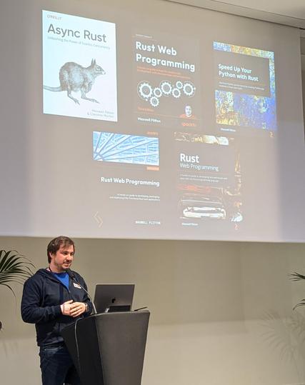 Maxwell in front of the 5 books he wrote around Rust.