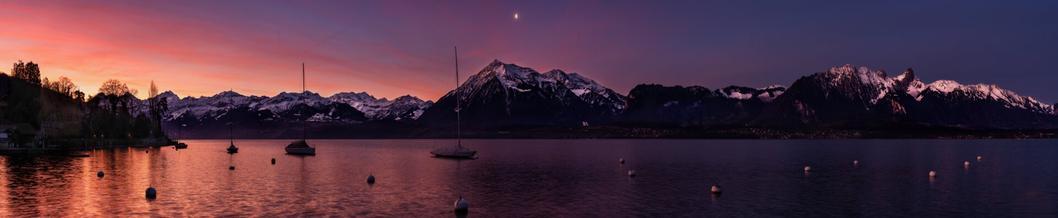 Panoramaaufnahme der Morgendämmerung am Thunersee mit den Berner Alpen und Voralpen