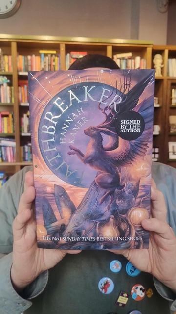 Bookseller Joe holding up a copy of Faithbreaker by Hannah Kaner, in the Edinburgh Bookshop