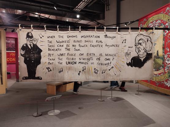 The reverse of the LGSM banner, showing the lyrics of "Solidarity Forever" and excellent caricatures of a policeman and Margaret Thatcher.