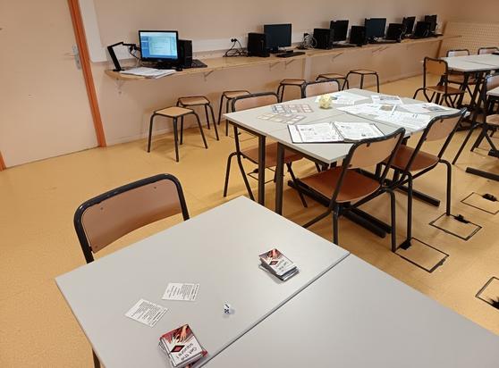 Photographie de table avec le jeu de cartes get the square et en fond d'image un visualiseur au-dessus d'un cahier.