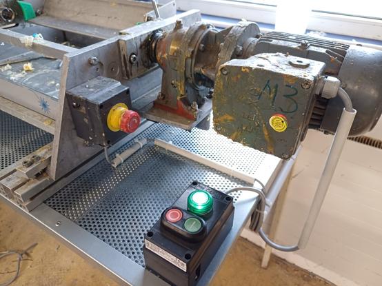 A workbench with extraction through the perforated sheet. A motor is connected to the machine. There is also an emergency stop button and a control panel with an on/off switch, as well as an indicator light for release. All components are suitable for the explosion-proof area.