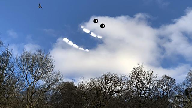 A photo of a blue sky with a large white fluffy cloud, dark trees below, and a bird flying above. The cloud has a hollow on the left hand side, to which I had added flat teeth so it forms an open mouth, and have added eyes above. It is gazing at the bird flying by. It looks happy. Whether it is excited to see the bird, or excited at the prospect of eating the bird, we do not know (although they are not the teeth of a predator, so I suspect the former).