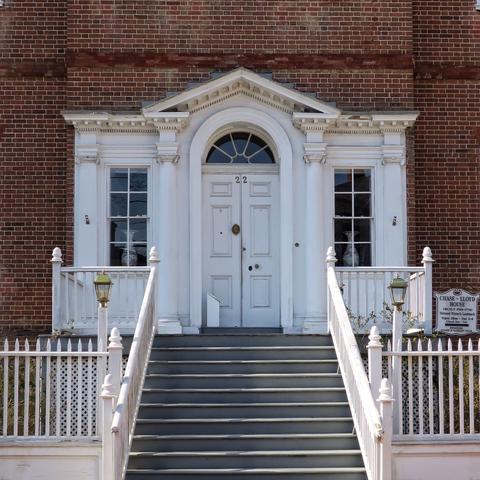 Steps with white fencing lead to a very fancy white double-door with lunette window in a Colonial brick house of an obviously prominent citizen of the city.