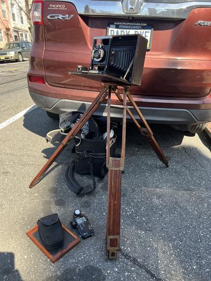 A Seneca 8 set up on my old wooden folding Graflex tripod, with a light meter and film holder laying on the ground in front.