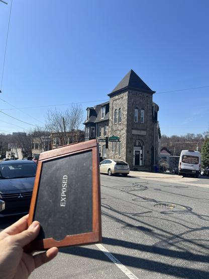 Cell phone photo of the Men’s Club building in the previous post with me holding up an antique 5x7 holder in the foreground with the word “Exposed” visible.