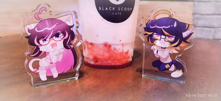 thick acrylic standees of two cats between a strawberry and cream frappe
