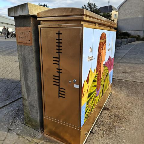 Side view of the box, painted gold with "SCOTIA" in ogham