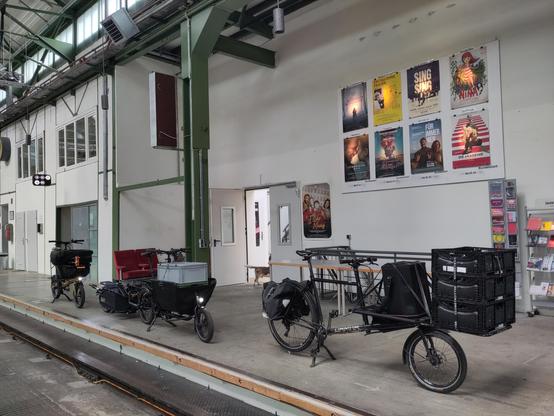 Voll beladene Lastenräder stehen vor einer Wand mit Filmplakaten