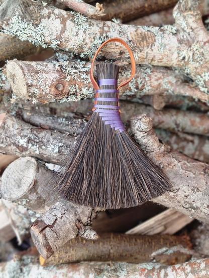 turkey wing broom with purple thread and dark brown straws.
