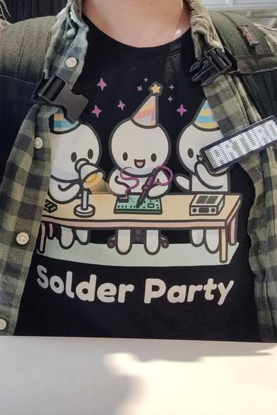 Selfie from neck down showing me wearing the solder party t-shirt, a green shirt and an led name tag saying Arturo