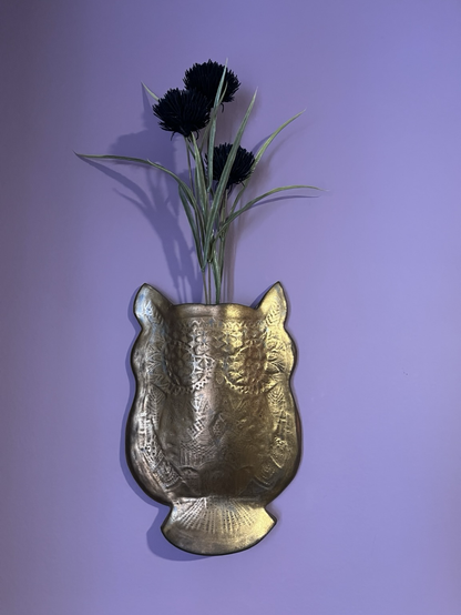 The owl vase is mounted on a purple wall