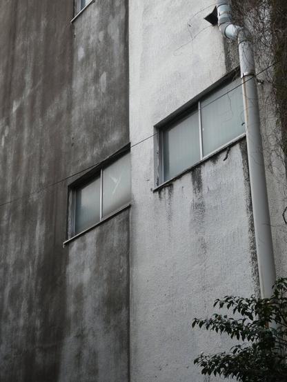 A concrete wall, the left is darker grey and the right lighter. There are two windows that make it look like a face of a robot