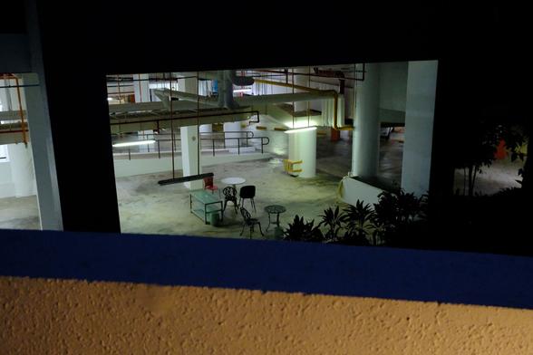 View into a carpark at night, with chairs and tables set in a space for workers.