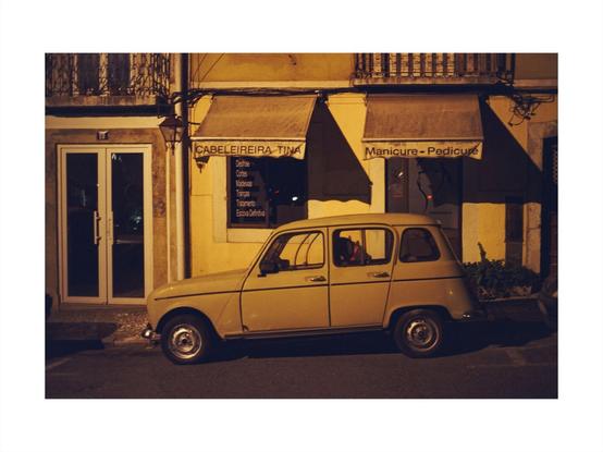 an old car at night in front of a manicure salon in lisbon, set in sepia colored tones