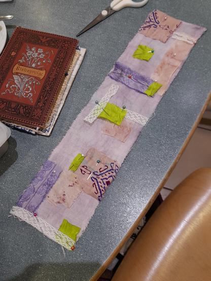 The beginning of a scroll book: The fabric is brightly purple (dyed with fruit tea). I placed different scraps from saree silk and lace on it and will fix them with "wild", intuitive embroidery like a collage. Colour spectrum: purple, rose, and yellowish green. These scroll books will be fixed on the wooden spools. They can be read like a Torah or hanged open on a wall.