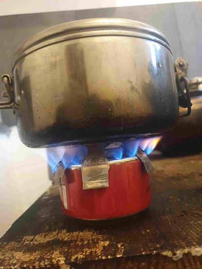 Réchaud à alcool en canette alu avec dessus une casserole de camping.