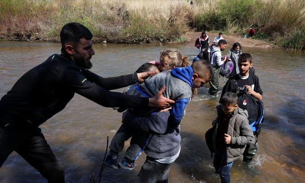 Un hombre ayuda a cruzar el río Nahr El Kabir a una familia escapada de violencia en el oeste de Siria, a la altura de Akkar (Líbano), el 11 de marzo de 2025. (Mohamed Azakir / Reuters)