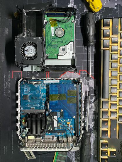 the original Mac Mini on a desk, case open, mainboard, hard drive, wireless interface, fan shown