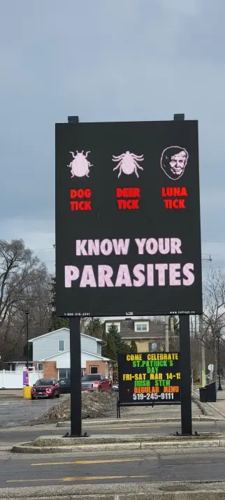 "Know your parasites" spring warning sign displaying;
- Dog tick (image of common tick)
- Deer tick (image of deer tick)
- Luna Tick (image of Donald Trump)