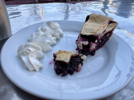 wild blueberry pie (broken in two pieces) and whipped cream on a plate