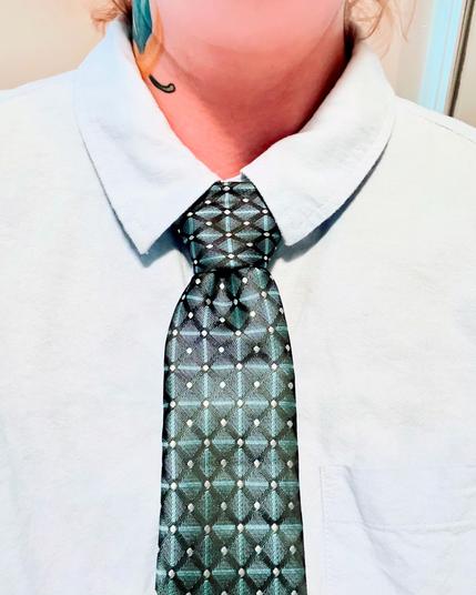 Close-up of a teal and silver necktie, tied in a Pratt knot.