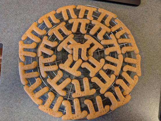 An overhead photo of a baking rack holding 31 (π x 10?) pi-shaped crackers.