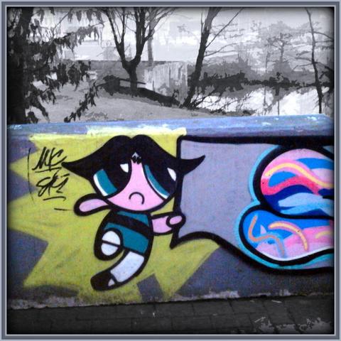 Stark mit Gimp bearbeitetes Foto eines farbenfrohen Graffito auf einer niedrigen, grauen, maroden Betonwand. Die gesamte Landschaft dahinter ist entfärbt worden.